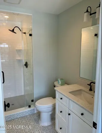 a bathroom with a granite countertop sink a toilet and shower