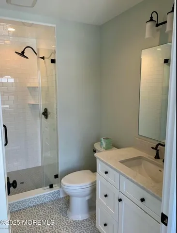 a bathroom with a granite countertop sink a toilet and shower