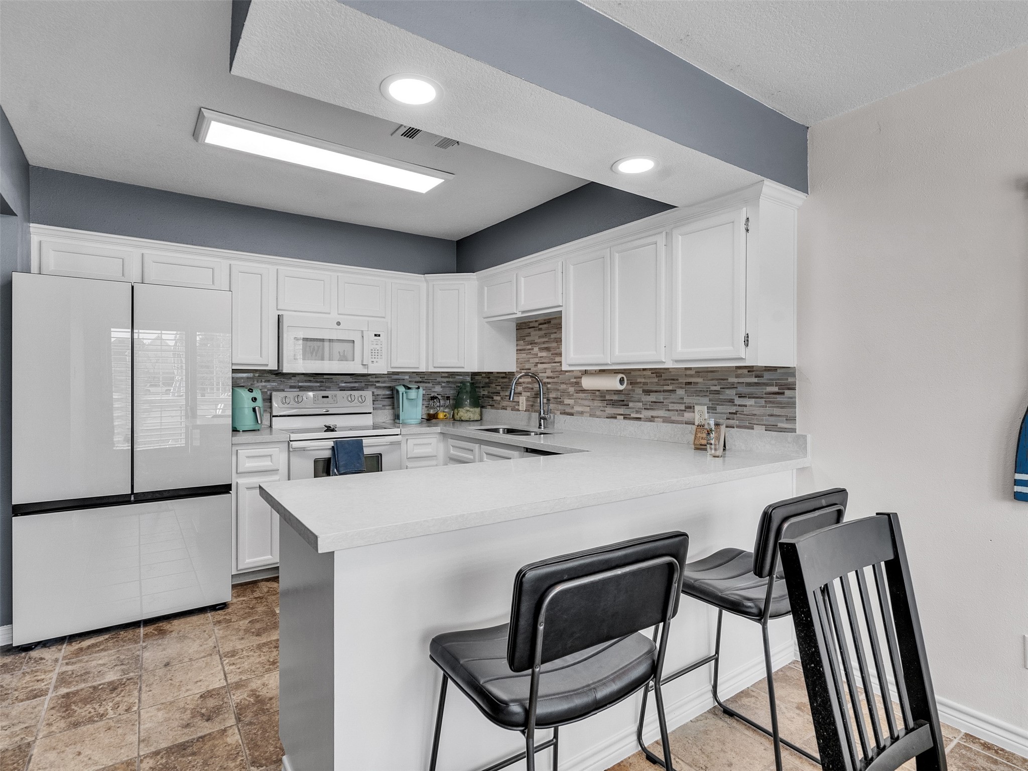 10109 Schaper Road Galveston, TX 77554 - Photo 7 of 33 a kitchen with stainless steel appliances granite countertop a stove a refrigerator a sink a stove with white cabinets and wooden floor