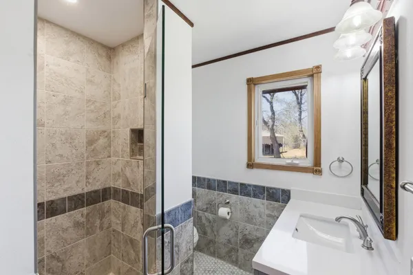 a bathroom with a tub shower sink and mirror