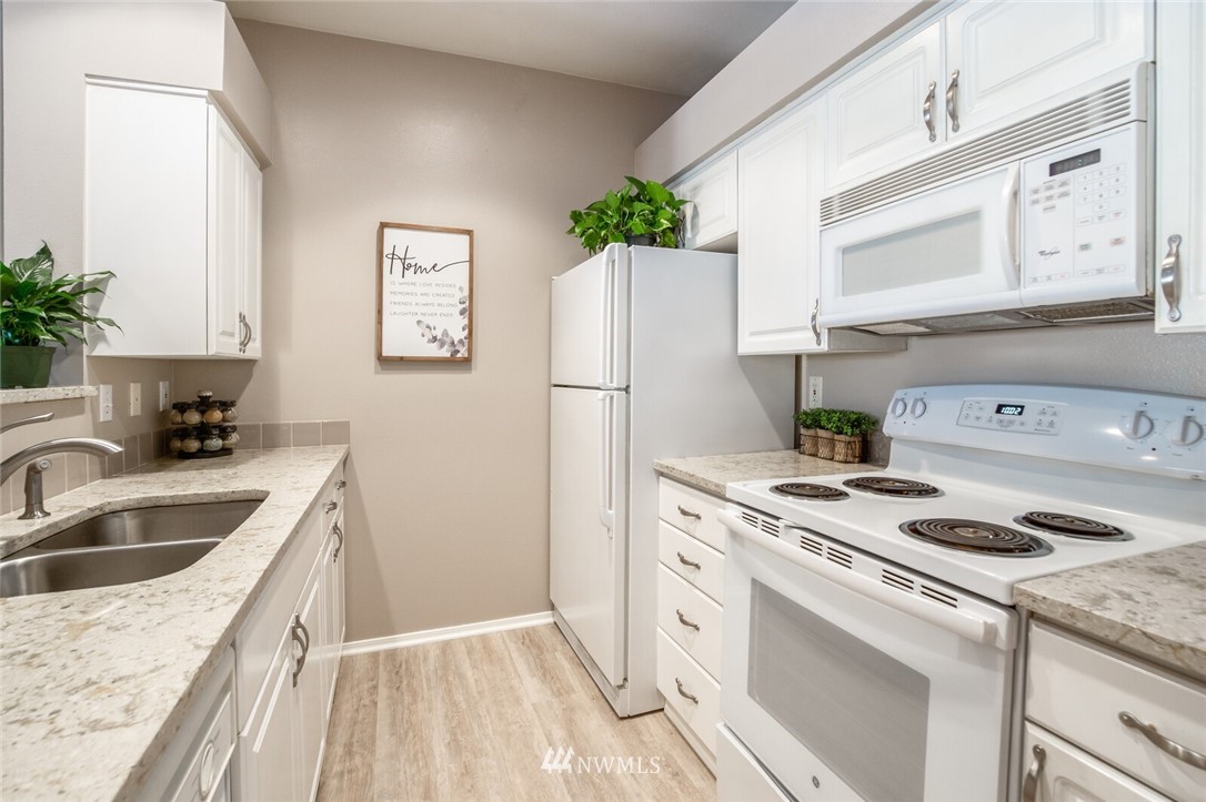 23908 Bothell Everett Highway, Unit A103 Bothell, WA 98021 - Photo 6 of 20 a kitchen with a sink dishwasher a refrigerator a stove and a cabinets with wooden floor