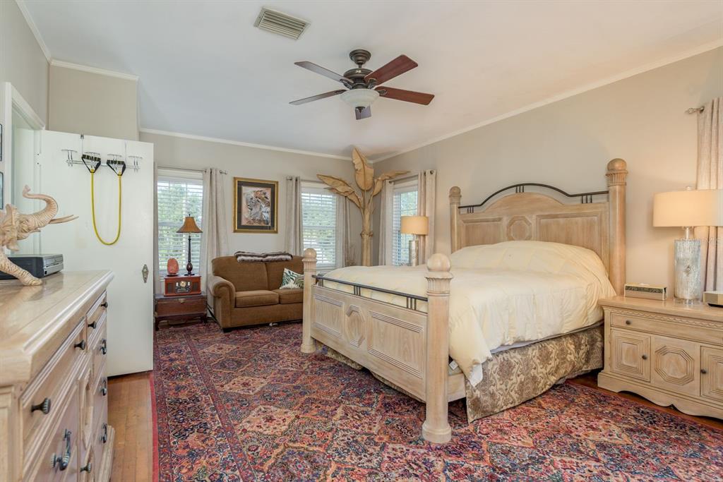 1111 West Line Street Leesburg, FL 34748 - Photo 32 of 77 a spacious bedroom with a bed and a chandelier
