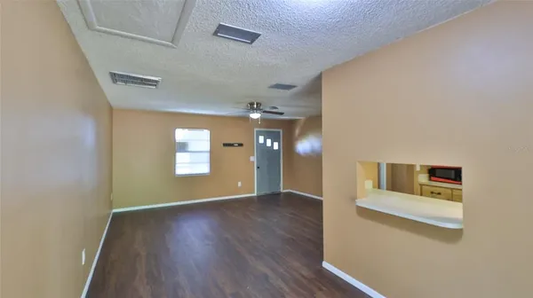 a view of an empty room with window and wooden floor