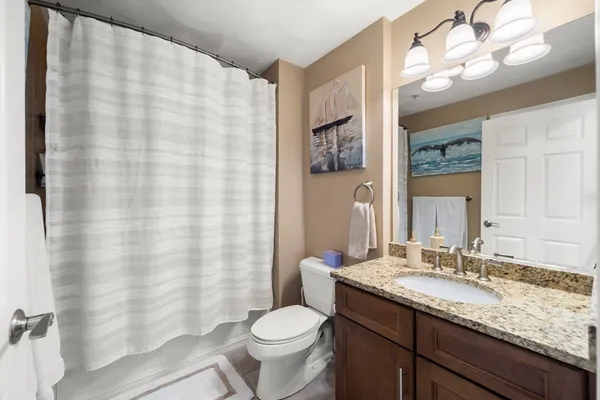 a bathroom with a granite countertop sink toilet and a mirror