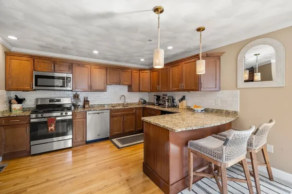 a kitchen with kitchen island granite countertop a stove a sink a microwave and wooden cabinets