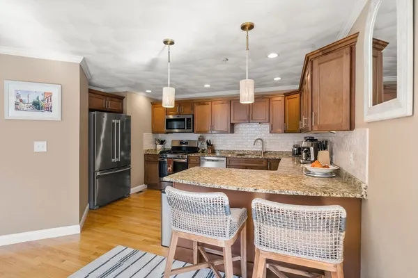 a kitchen with granite countertop a refrigerator a stove a sink a dining table and chairs with wooden floor
