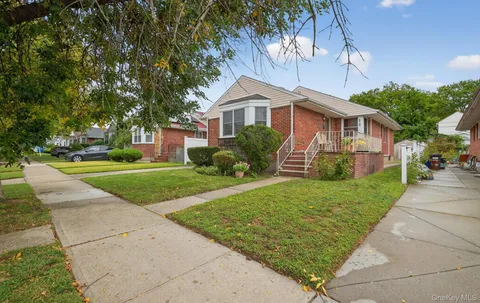 a front view of a house with a yard and potted plants