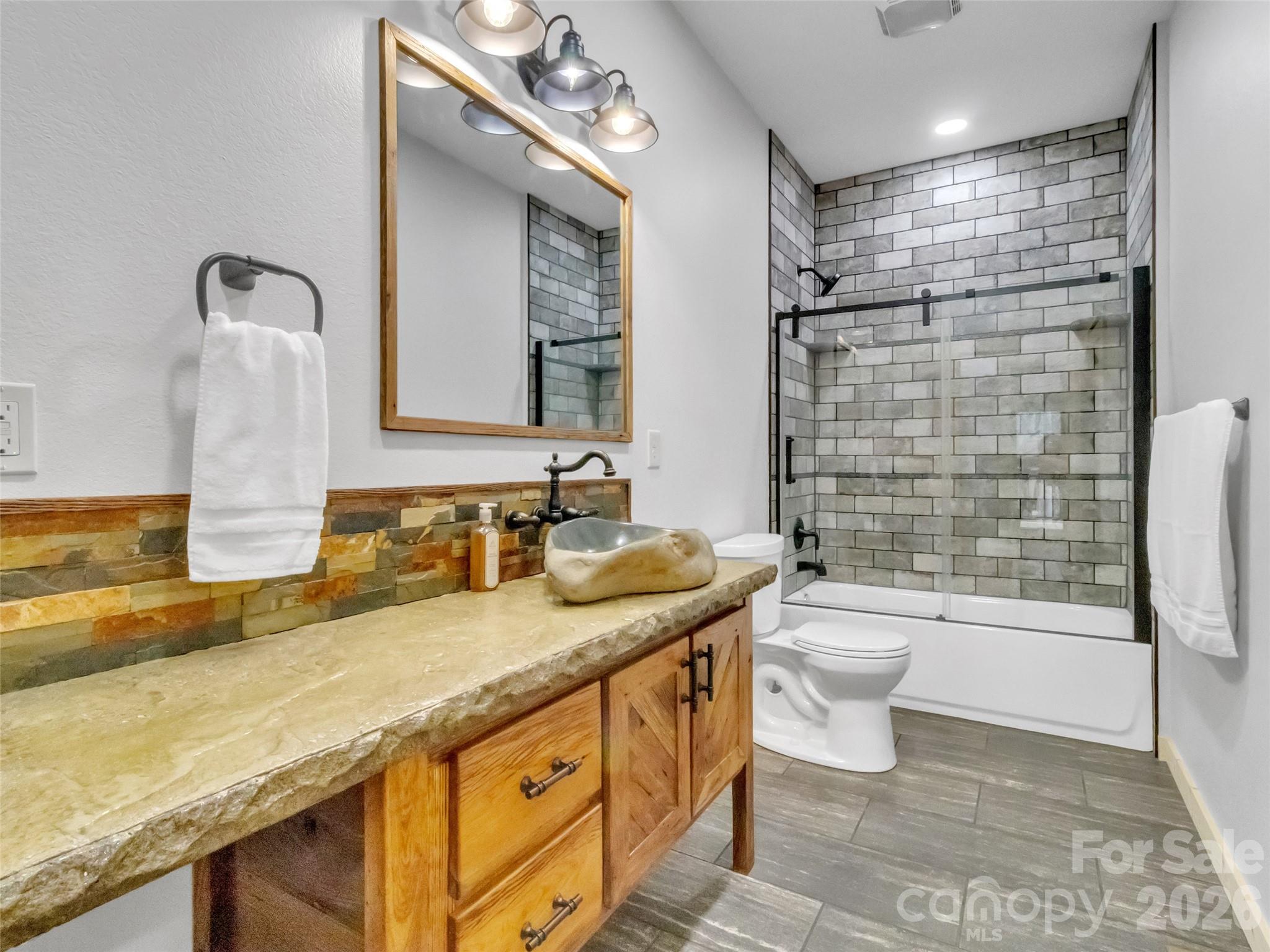 171 Cowtail Cove Clyde, NC 28721 - Photo 20 of 48 a bathroom with a granite countertop sink a toilet a mirror and bathtub