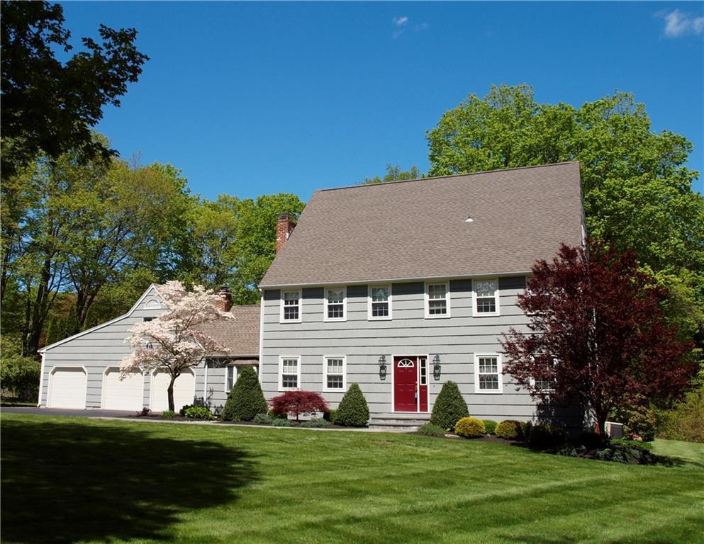 a view of a white house with a big yard and potted plants and large trees
