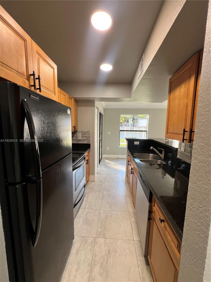 10670 Southwest 156th Place, Unit 309 Miami, FL 33196 - Photo 12 of 31 a kitchen with stainless steel appliances granite countertop a refrigerator a sink a stove and dishwasher