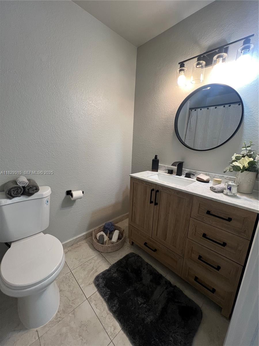 10670 Southwest 156th Place, Unit 309 Miami, FL 33196 - Photo 14 of 31 a bathroom with a toilet mirror vanity and sink