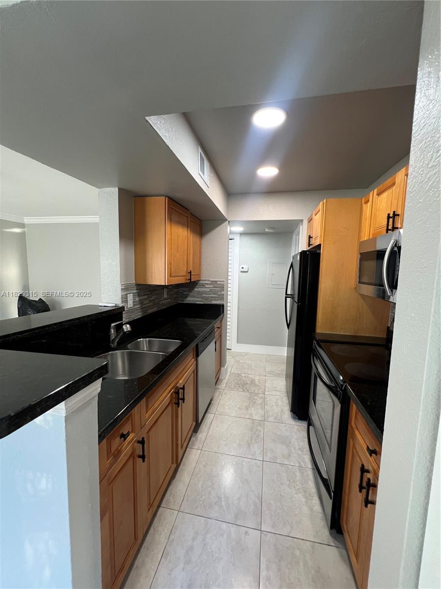 10670 Southwest 156th Place, Unit 309 Miami, FL 33196 - Photo 10 of 31 a kitchen with granite countertop a sink and stainless steel appliances