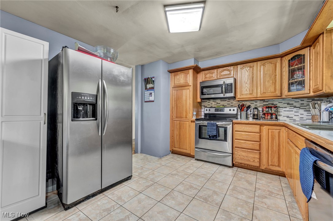 11996 Bower Road East Rochester, OH 44625 - Photo 9 of 49 Kitchen with stainless steel appliances, decorative backsplash, glass insert cabinets, and light tile patterned flooring