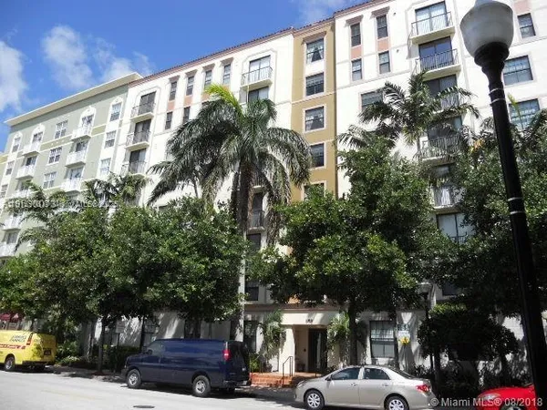 a front view of a building with parking space and palm trees
