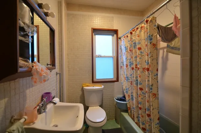 a white toilet sitting next to a bathroom sink and a shower