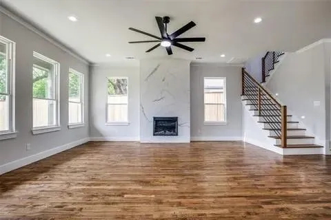 a view of a livingroom with a fireplace a ceiling fan and wooden floor