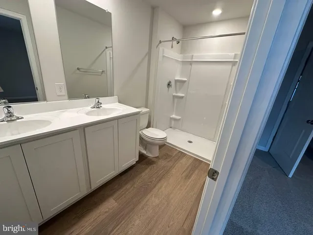 a bathroom with a double vanity sink toilet mirror and shower
