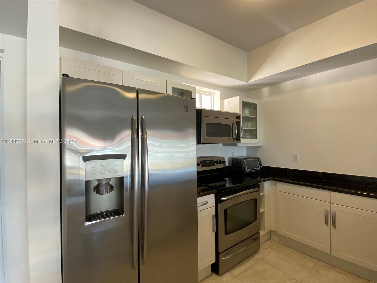 7270 Southwest 88th Street, Unit B502 Miami, FL 33156 - Photo 3 of 20 a kitchen with a refrigerator and white cabinets