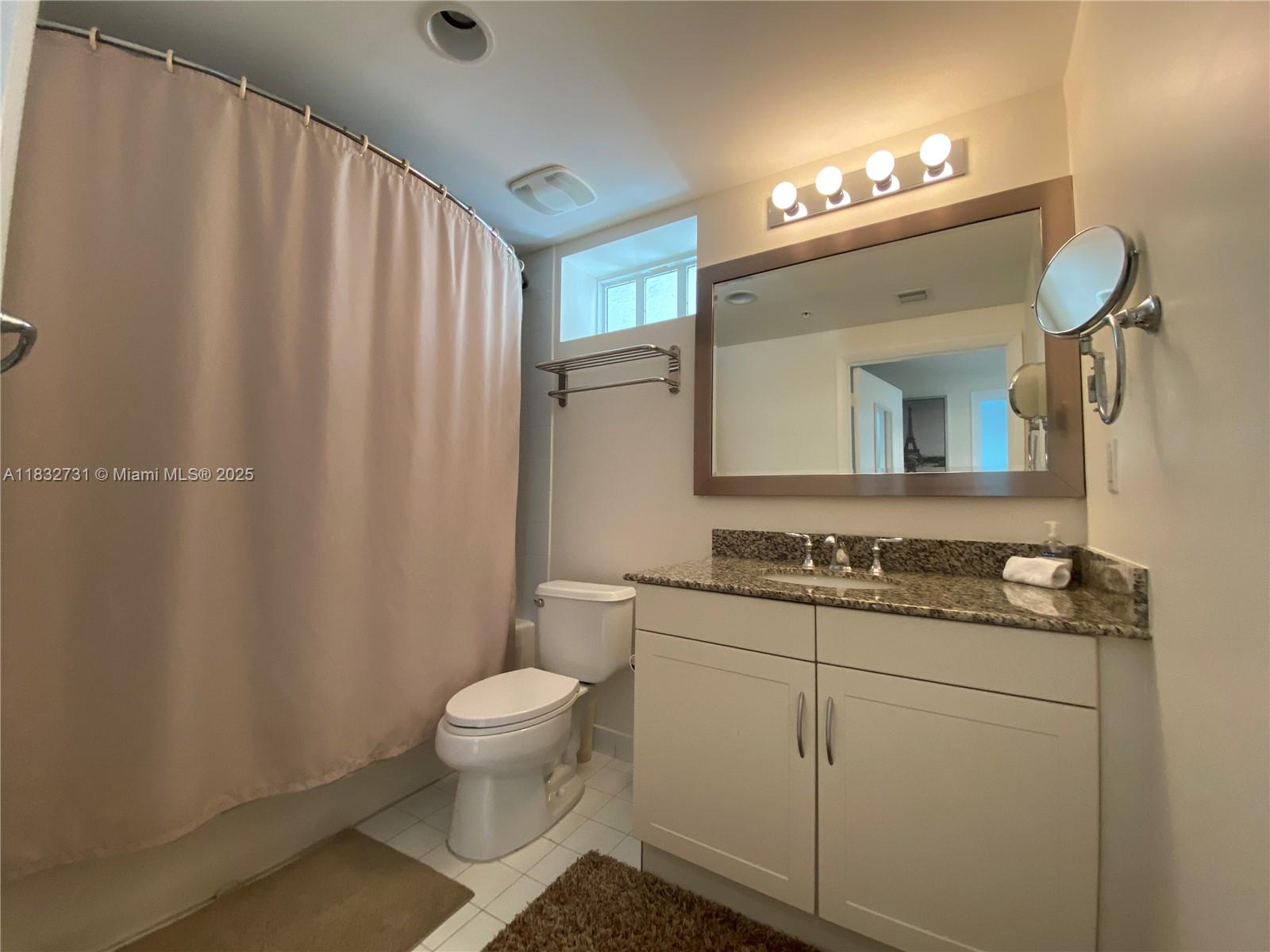 7270 Southwest 88th Street, Unit B502 Miami, FL 33156 - Photo 10 of 20 a bathroom with a granite countertop sink a toilet and a mirror