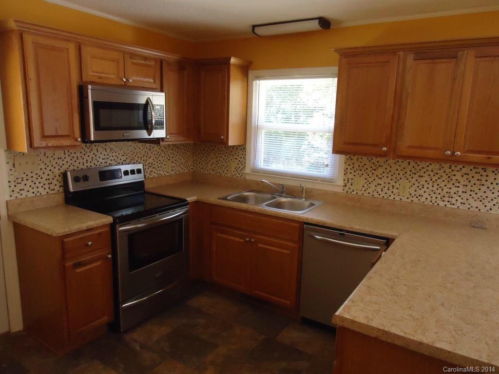 405 Absher Road Bessemer City, NC 28016 - Photo 14 of 15 a kitchen with granite countertop wooden cabinets and a stove top oven