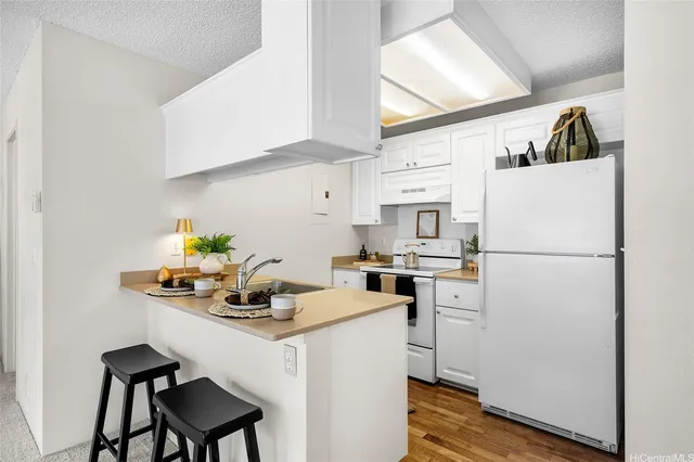 a kitchen with stainless steel appliances a refrigerator a sink a stove and white cabinets