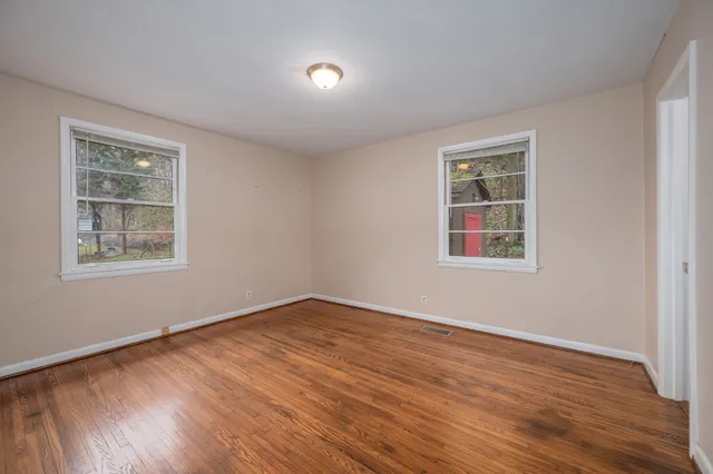 an empty room with wooden floor closet and windows