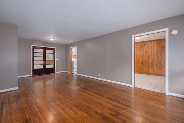 a view of an empty room with a window and wooden floor