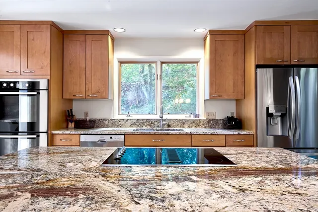 a kitchen with stainless steel appliances granite countertop a refrigerator a sink a stove a microwave and wooden cabinets