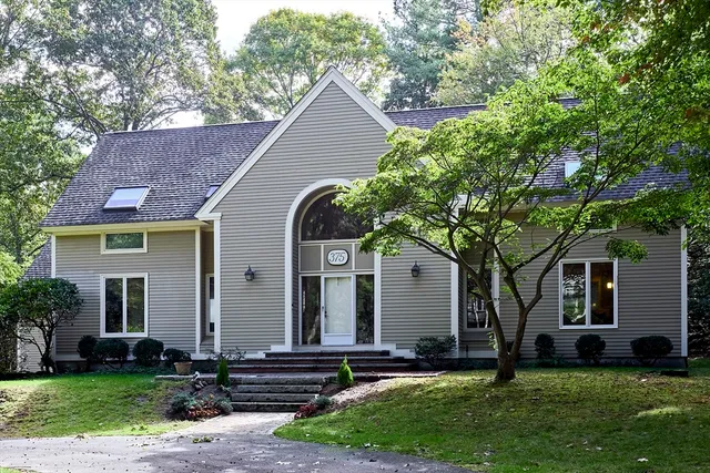 a front view of a house with a yard and tree