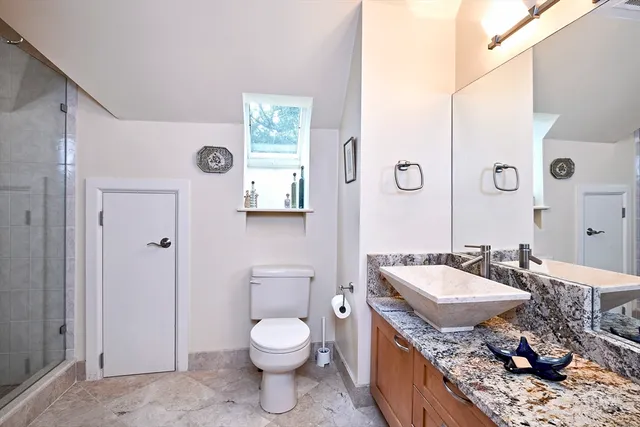 a spacious bathroom with a granite countertop sink a toilet and a large mirror
