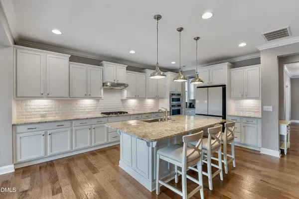 a kitchen with kitchen island a stove a table and chairs in it