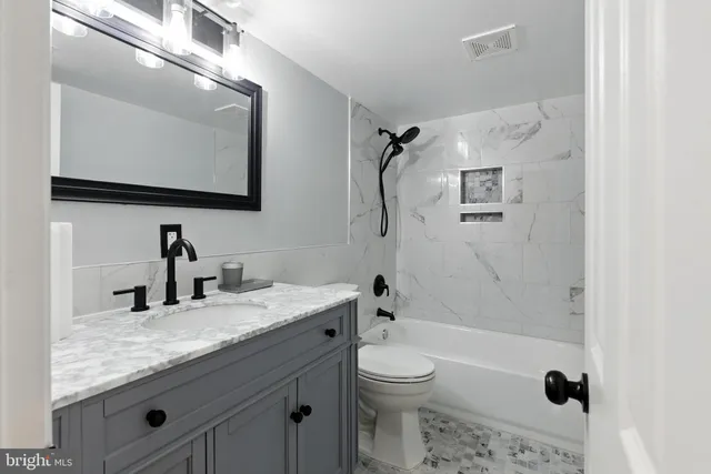 a bathroom with a granite countertop sink a mirror and a bathtub