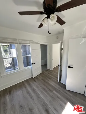 a view of an empty room with a window and wooden floor