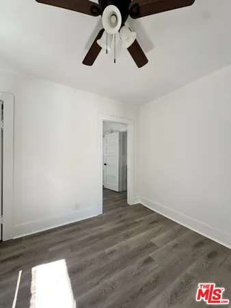 an empty room with wooden floor ceiling fan and window