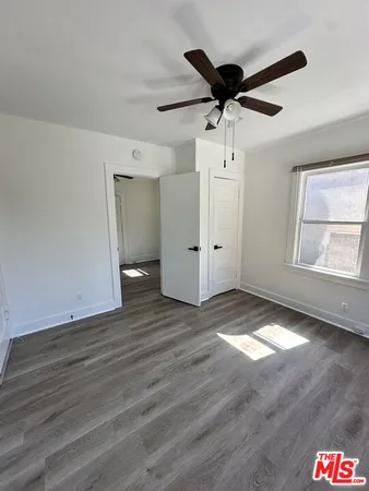 a view of empty room with wooden floor and ceiling fan
