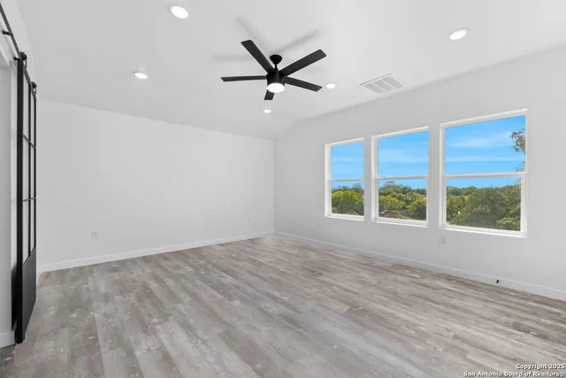 an empty room with windows and fan