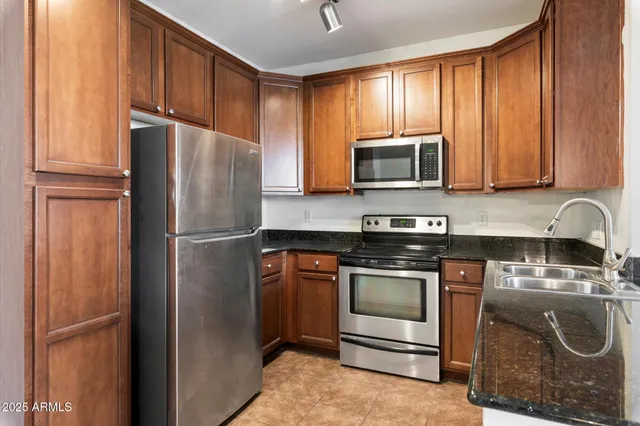 a kitchen with granite countertop wooden cabinets and stainless steel appliances