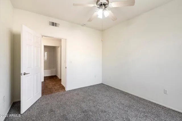 an empty room with a ceiling fan and a bathroom