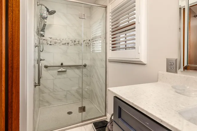 a bathroom with a granite countertop sink a mirror and shower