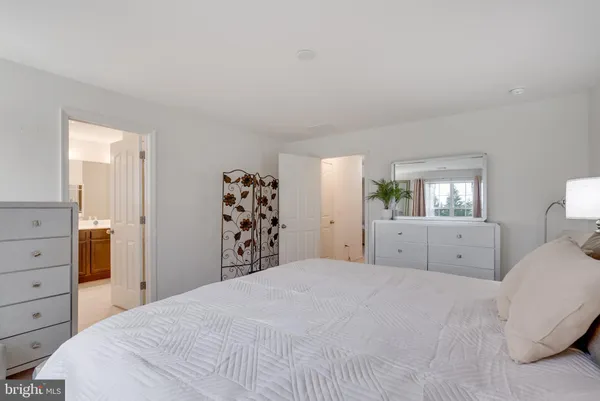 a bedroom with a large bed and dresser with mirror