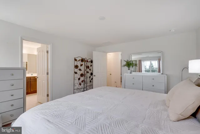 a bedroom with a large bed and dresser with mirror