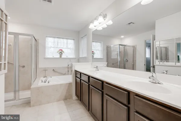 a spacious bathroom with a bathtub double sink shower and mirror