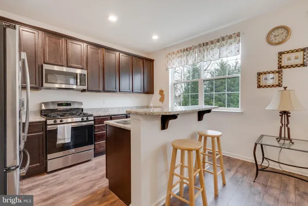 a kitchen with stainless steel appliances granite countertop a stove a sink a microwave and wooden cabinets