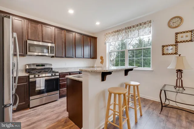 a kitchen with stainless steel appliances granite countertop a stove a sink a microwave and wooden cabinets