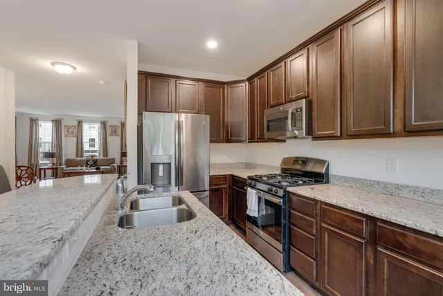 a kitchen with stainless steel appliances granite countertop a refrigerator a stove top oven a sink and dishwasher