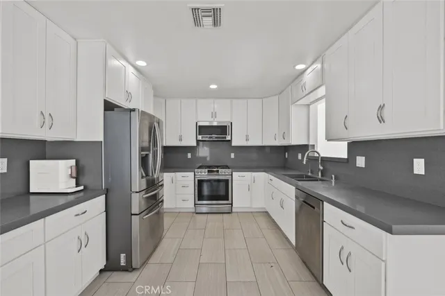 a kitchen with stainless steel appliances granite countertop a refrigerator stove a sink and dishwasher with white cabinets