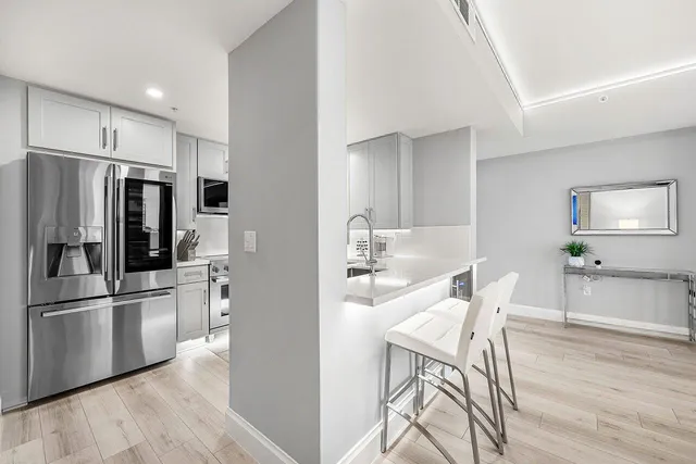 a kitchen with stainless steel appliances a refrigerator and wooden floor