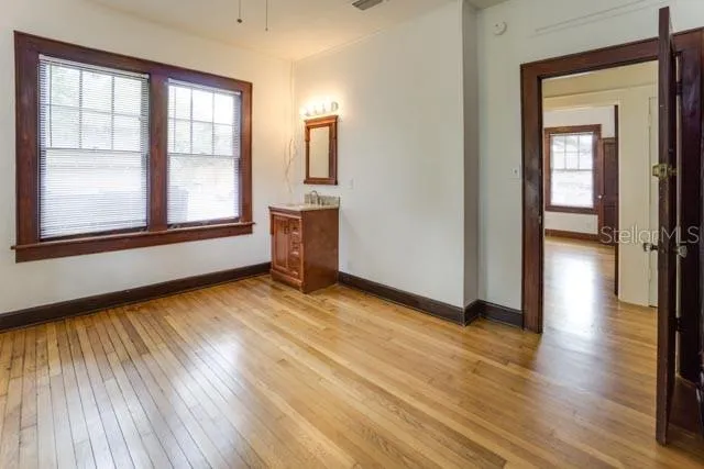 a view of empty room with wooden floor and fan