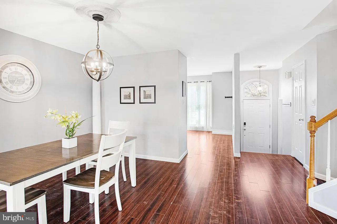 10864 Caraway Circle Manassas, VA 20109 - Photo 15 of 16 a view of a dining room with wooden floor a chandelier a wooden table and chairs
