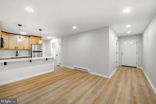a view of an empty room with wooden floor and a sink